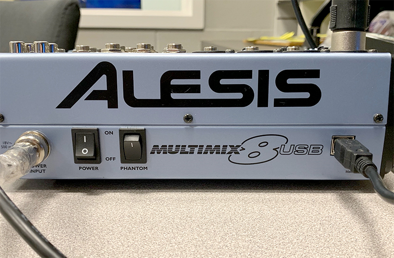 This is an image of the back of a mixer board with cords plugged in and two switches to turn on and off.