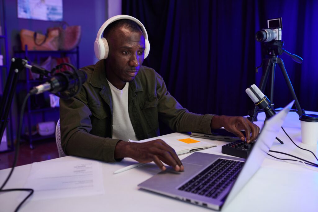 This is an image of a person sitting at a computer with headphones on editing at a computer.