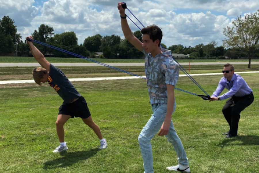 Photo of two boys and a teacher creating a giant slingshot
