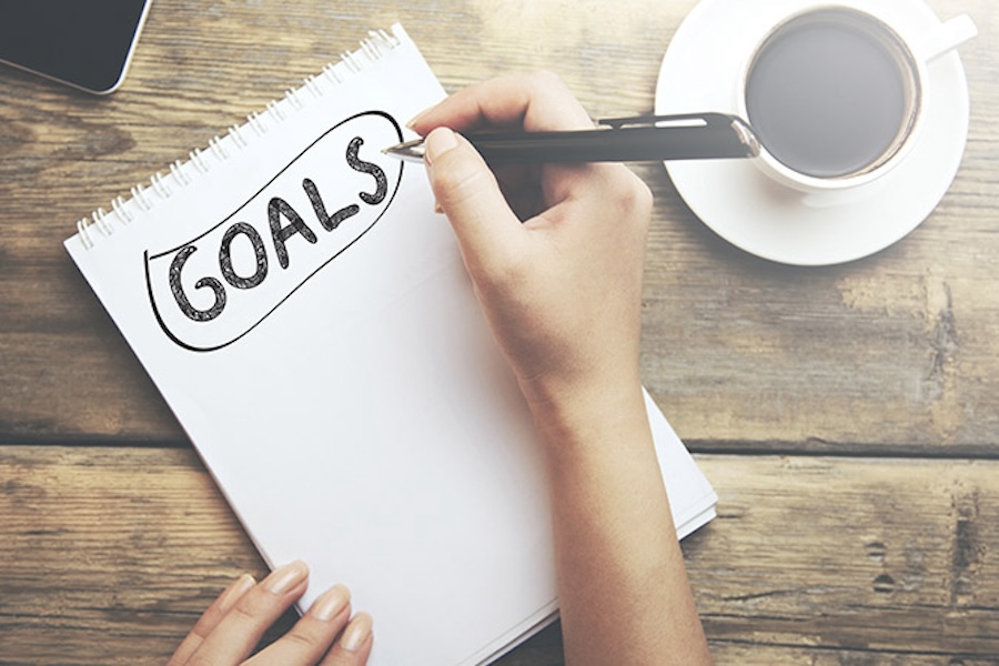 Photo of a person writing down goals in a notebook