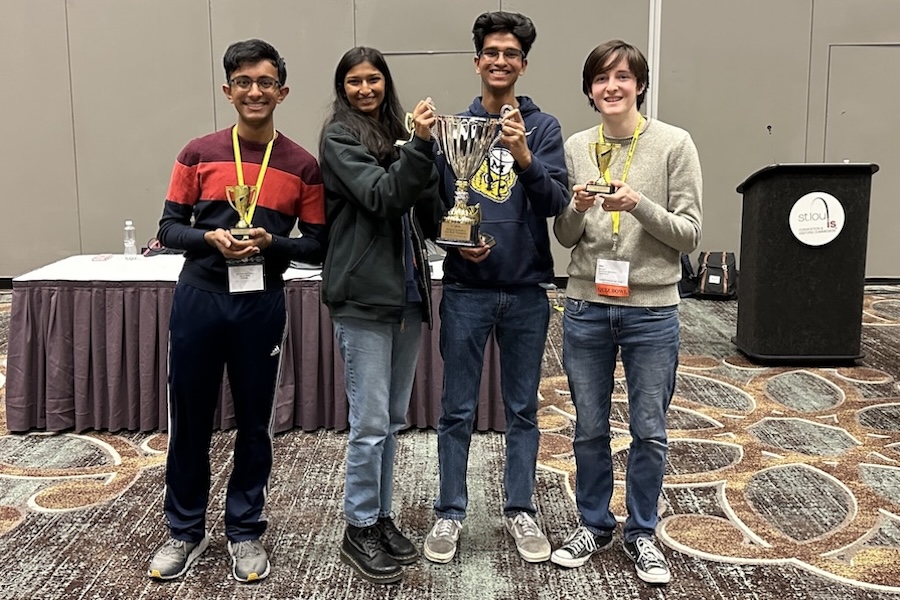 QuizBowl-2048x1500 4 students hold trophies after winning Quiz Bowl