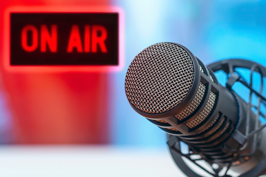 Image of a recording mic with the On Air sign in the background