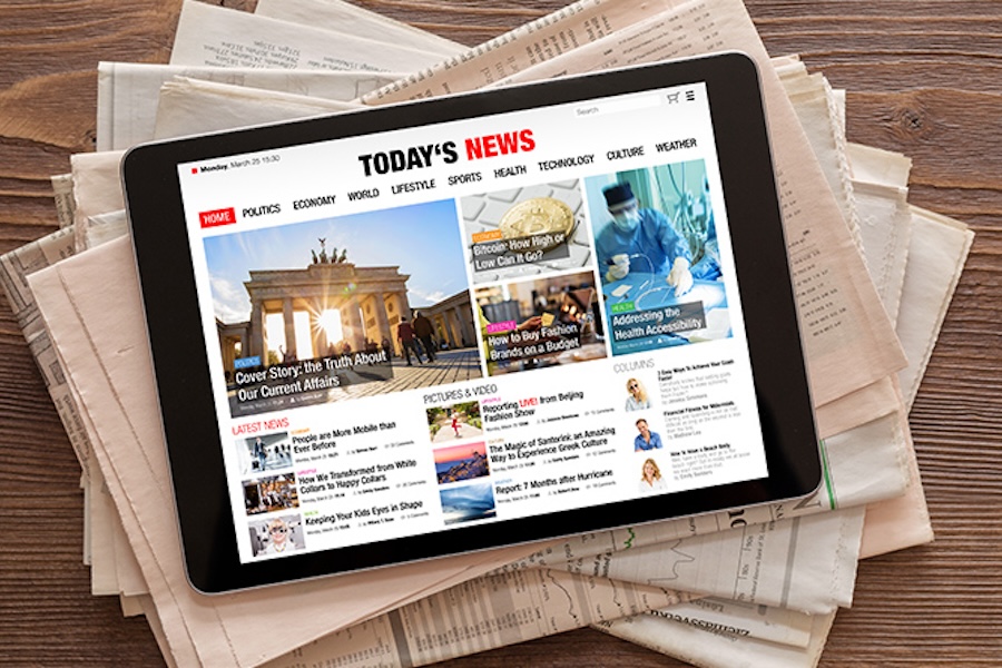 Photo of an ipad with a news website open on top of a stack of newspapers