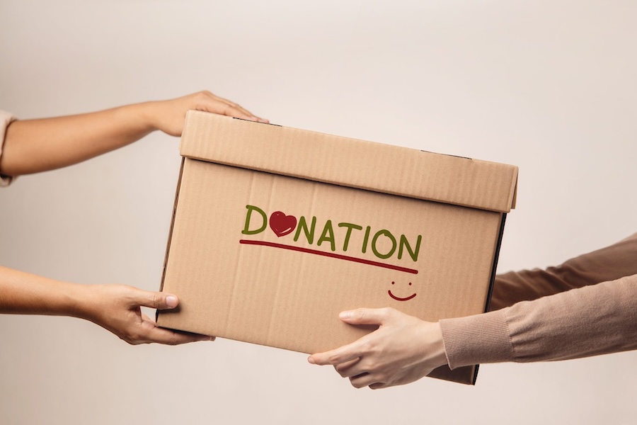 Someone handing someone else a cardboard box labeled donations.