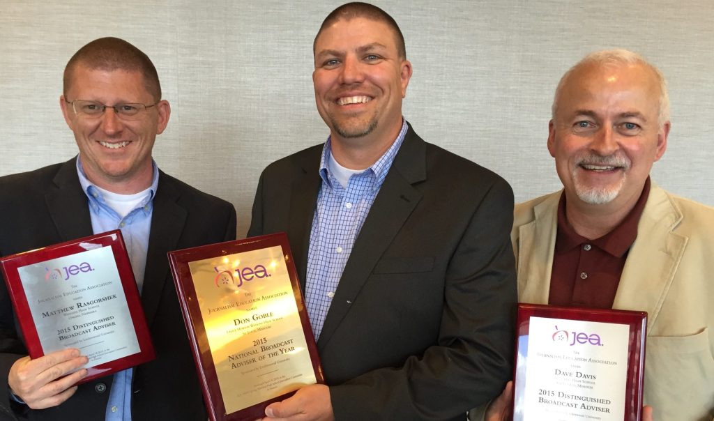 Photo of 3 men holding up plaques of various awards from JEA