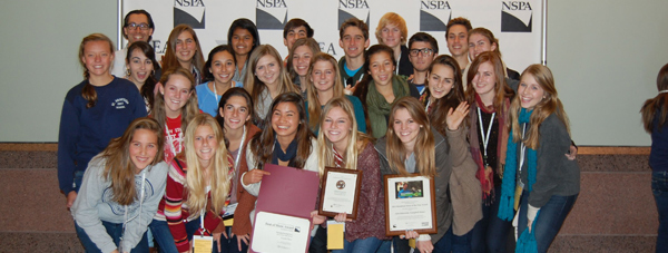 A group of students hold up various plaques and certificates at the NSPA/JEA National Convention