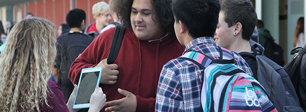 Photo of a girl holding an iPad to 3 students