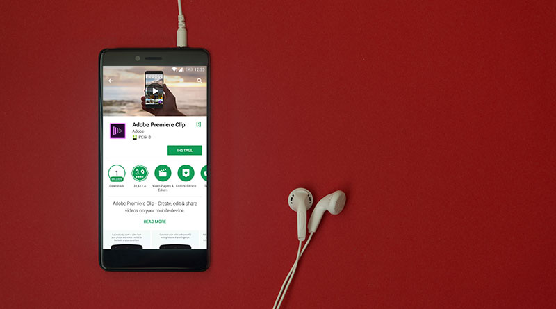 Photo of a phone downloading Adobe Premiere clip on with headphones