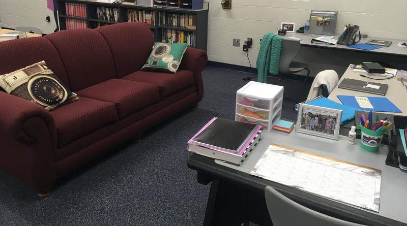 Photo of a newsroom with a couch and teachers desk with books