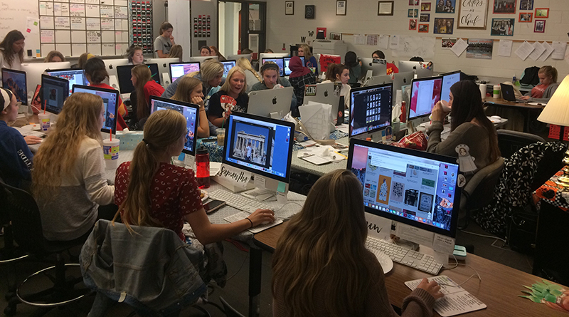 Photo of a full newsroom with students at computers and a teacher at her desk