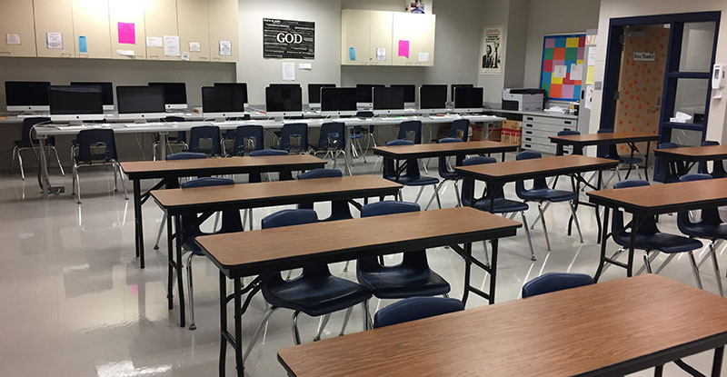 Photo of a newsroom that has rows of computers with pair desks facing the front of the room, the Door is decorated in hearts