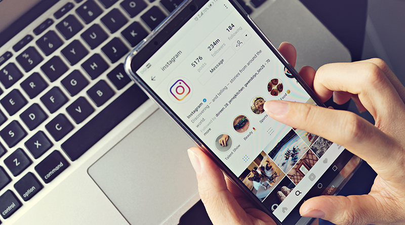 Photo of a iphone using instagram over a computer
