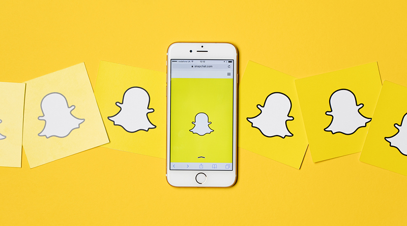 graphic that shows paper logos of Snapchat with a phone that shows the Snapchat logo