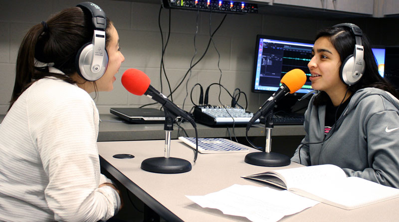 Photo of two girls recording a podcast