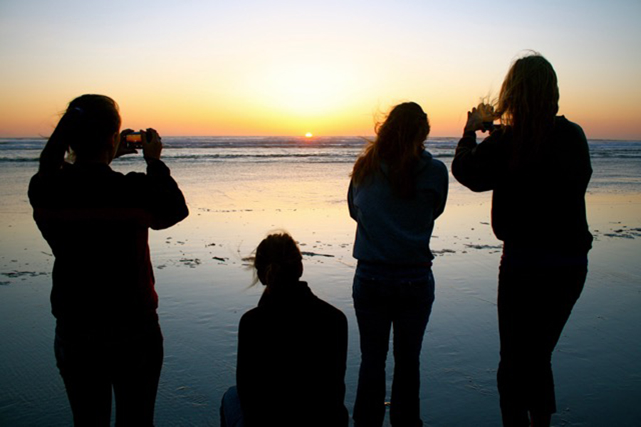 Photo of 4 girls taking a photo of a sunset on a beach