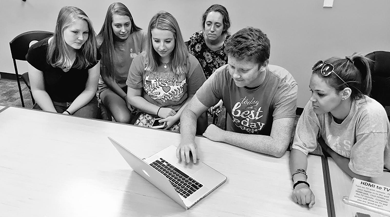 Black and white Photo of 6 students looking at one computer