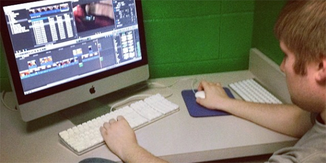 Photo of a student using Adobe Premiere on a desktop