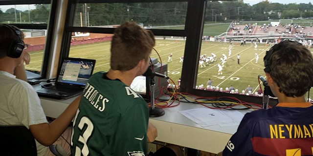 Photo of 3 boys livestreaming a high school football game