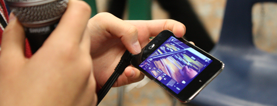 Photo of a person watching a video of a phone while holding a mic