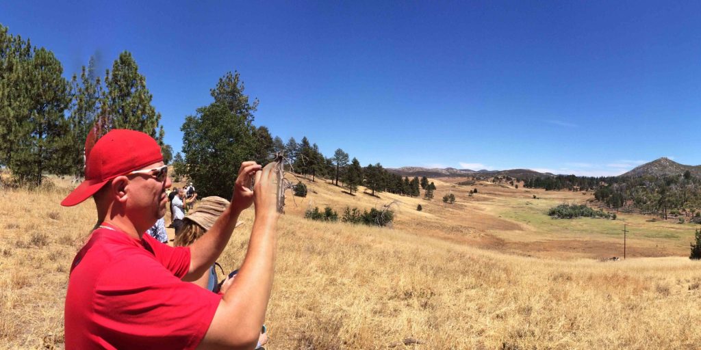 Photo of a man taking a photo of a dry, mountain-y landscape in Colorado