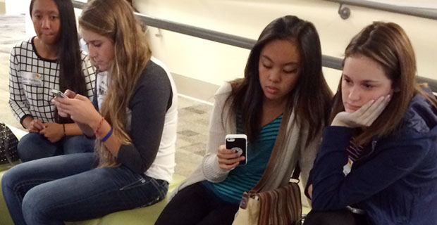 Photo of 2 pairs of girls looking at smarphones