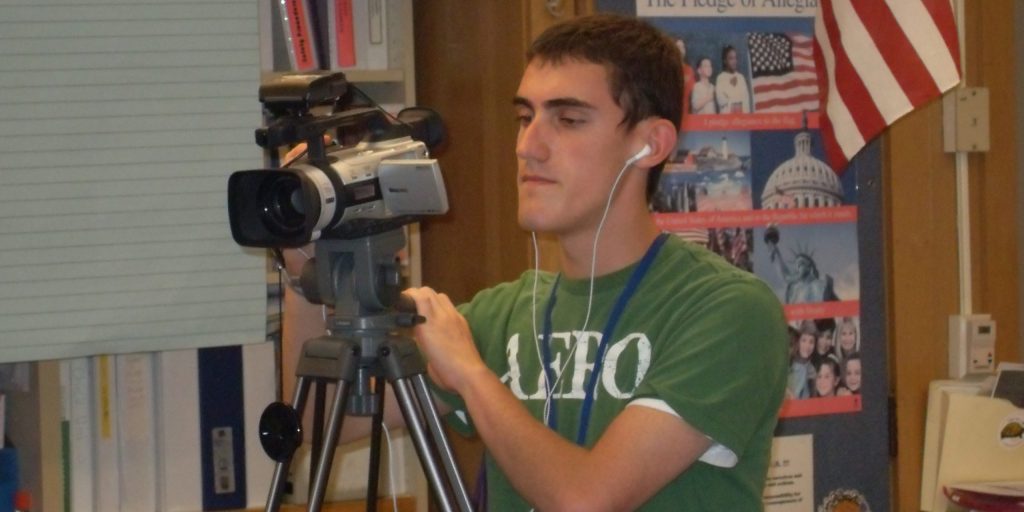 Photo of a man operating a camera in a classroom