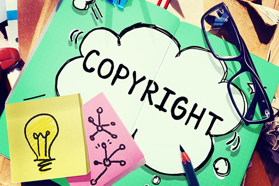 Illustration of a scattered desk that shows an open book that says copyright in quotes and there is post-it notes with a drawing of a light bulb and molecules.