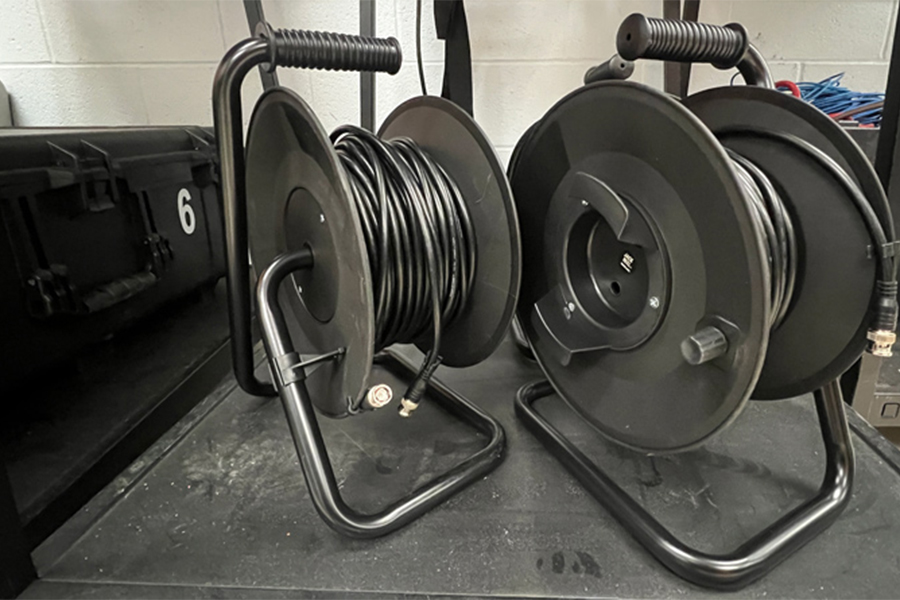 This is am image of two cable reels. The are black and there are cables wrapped around each of them.