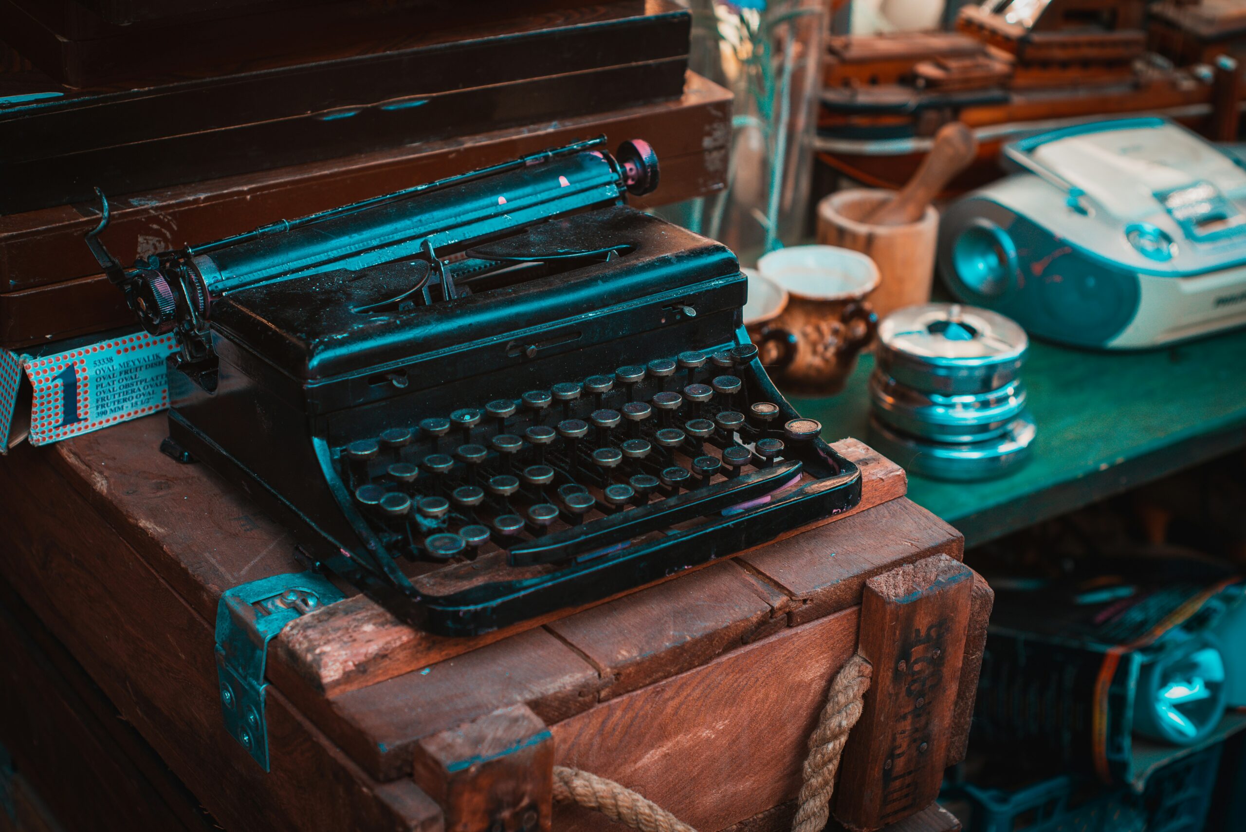 Image features an antique typewriter on an antique desk surrounded by desk supplies.