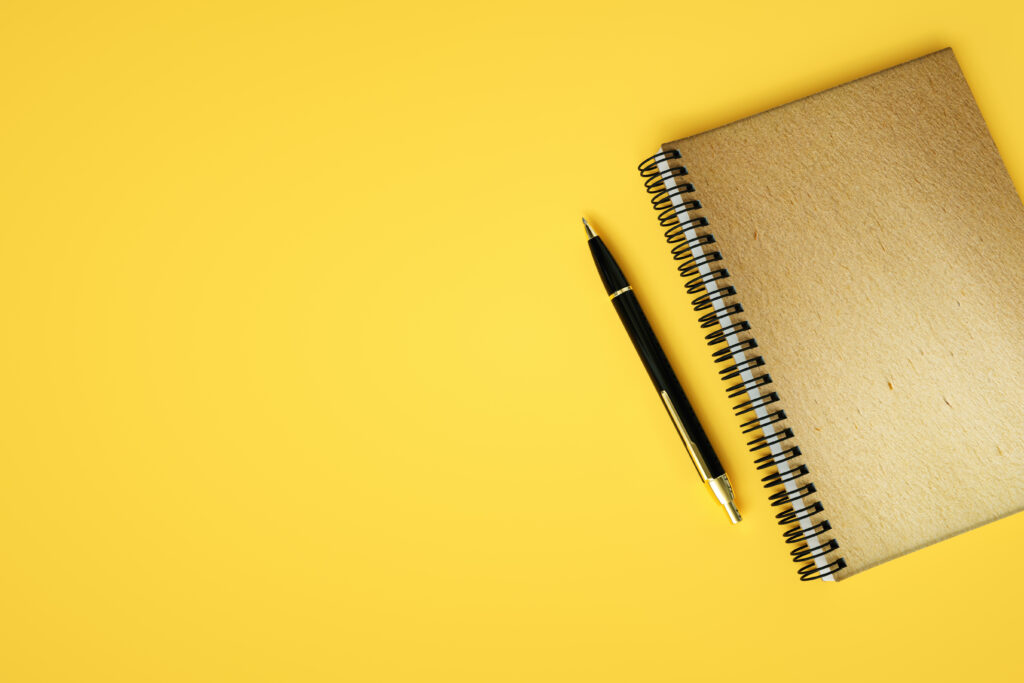 This is a yellow background. On the right side there is a pen and a notebook.