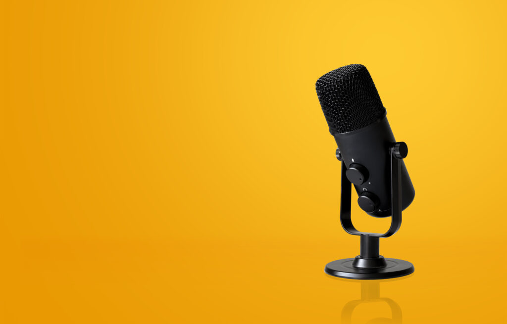 This is an image that includes a black microphone on the right side of the image and there is a yellow background behind the image.