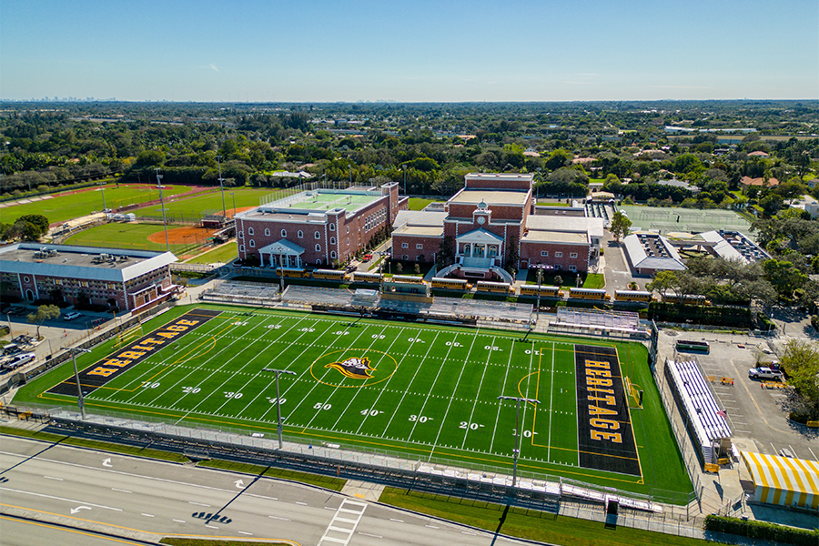 Aerial photography shot from a drone of a high school football field with the high school behind the field.